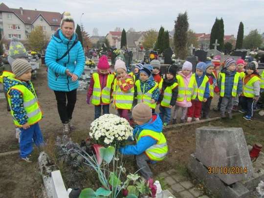 Przedszkolaki zapalają znicze i składają kwiaty